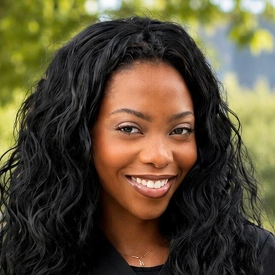 Outdoor headshot portrait of a person with long, curly hair
