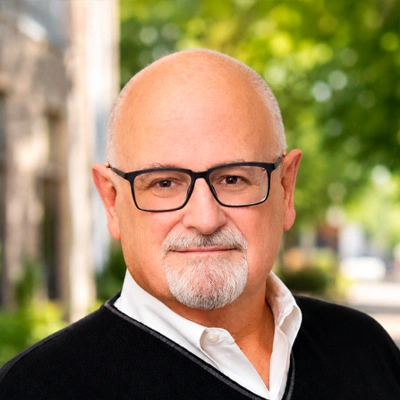 Outdoor headshot portrait of a person wearing glasses and a dark sweater